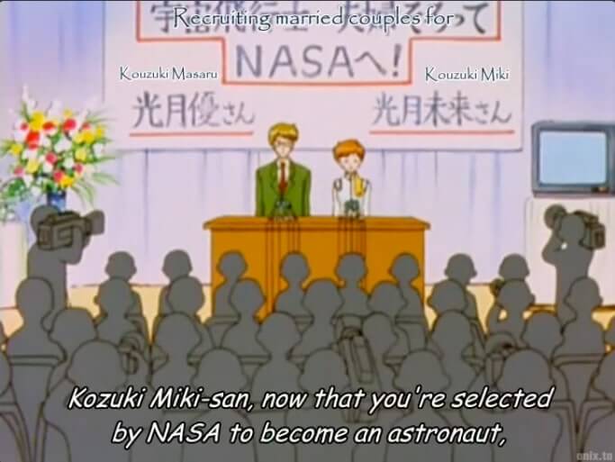 A man and woman standing at a podium in front of a crowd. The sign behind them reads RECRUITING MARRIED COUPLES FOR NASA! Kouzuki Masaru and Kouzuki Miki. This is written in the Papyrus font. The subtitled speech reads, Kozuki Miki-san, now that you're selected to become an astronaut, end subtitle. The subtitles are in Comic Sans font. Like the guys from Undertale. That's what I'm freaking out over.