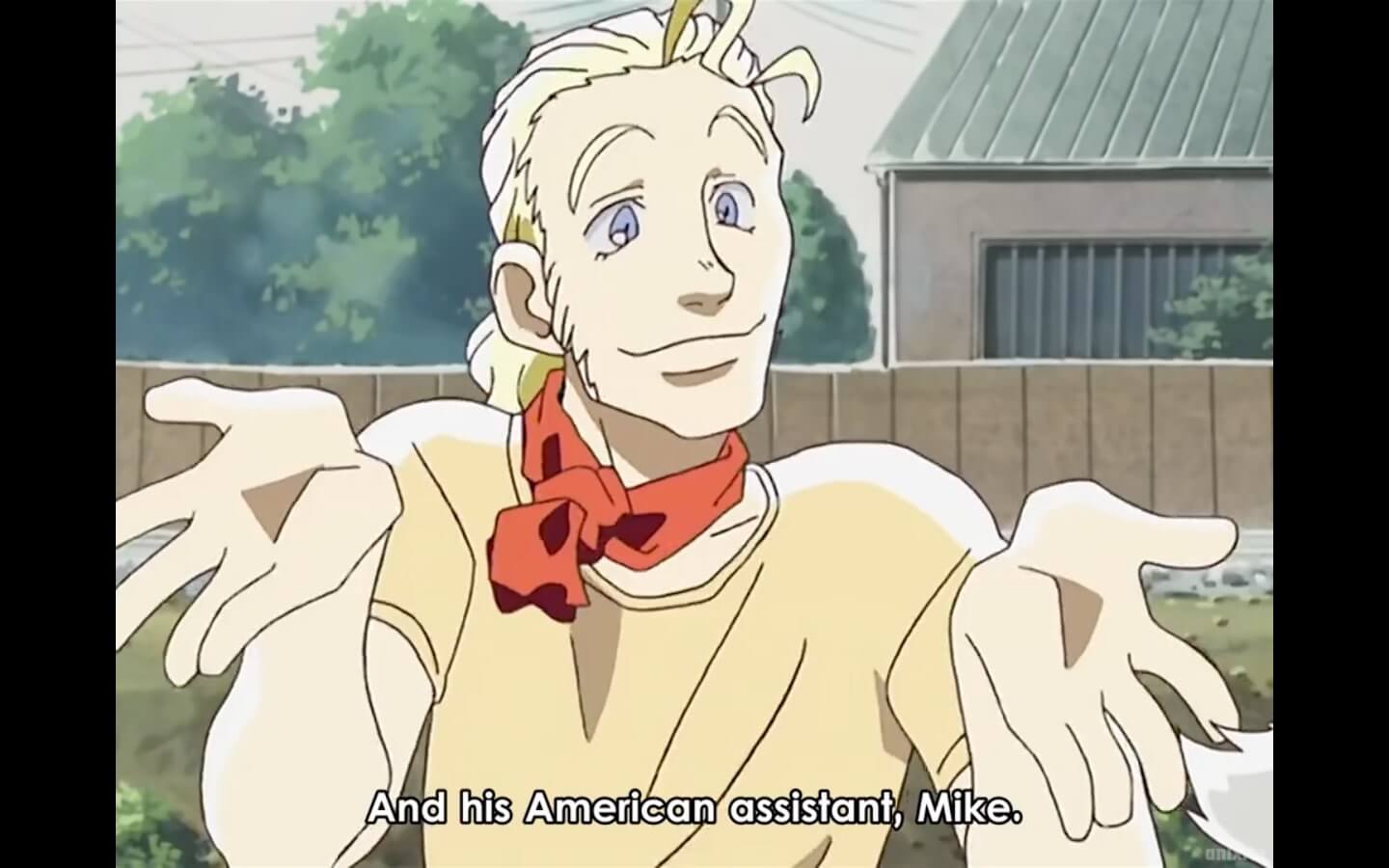 A pale blonde man with blue eyes, tied back hair and wearing a red handkercheif around his neck. Subtitles read, And his American assistant, Mike. End subtitle